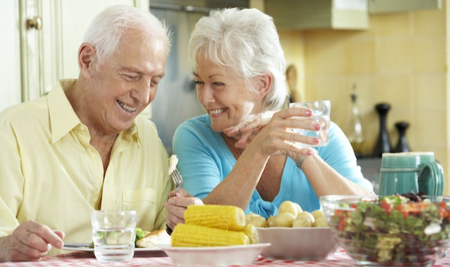 Older couple eating vegetables in a bright room